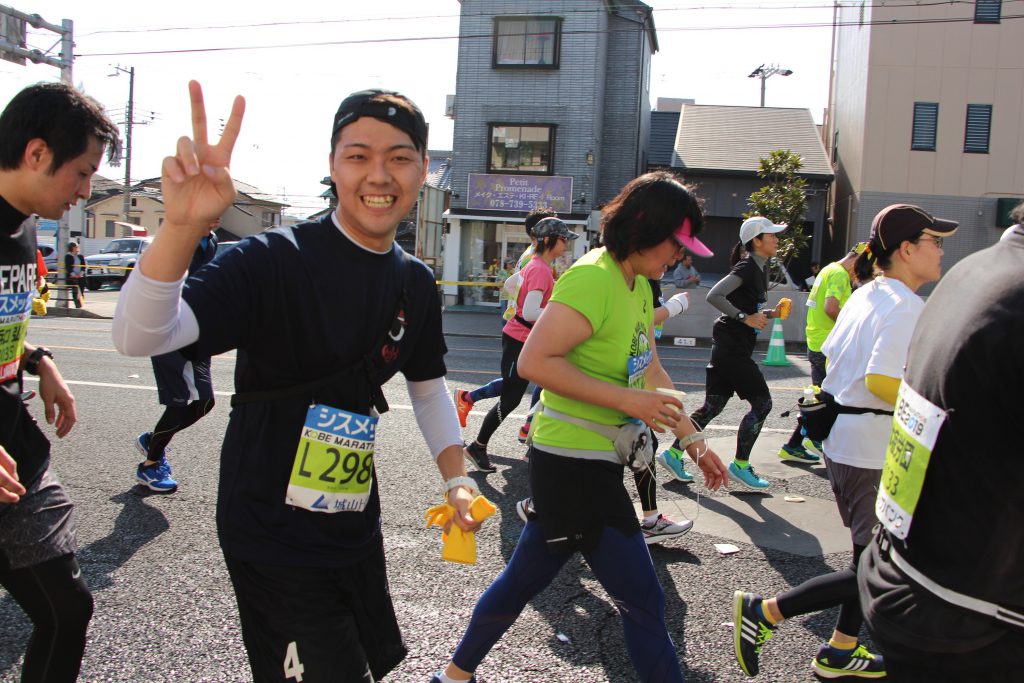 神戸マラソンにて須磨給水所で、笑顔で答えるQBBランナー。
